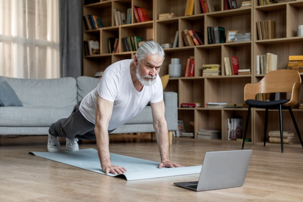 Senior man exercising by doing planks in his home