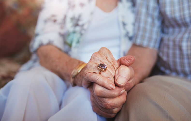 Elderly couple holding hands, symbolizing love and companionship in senior community.