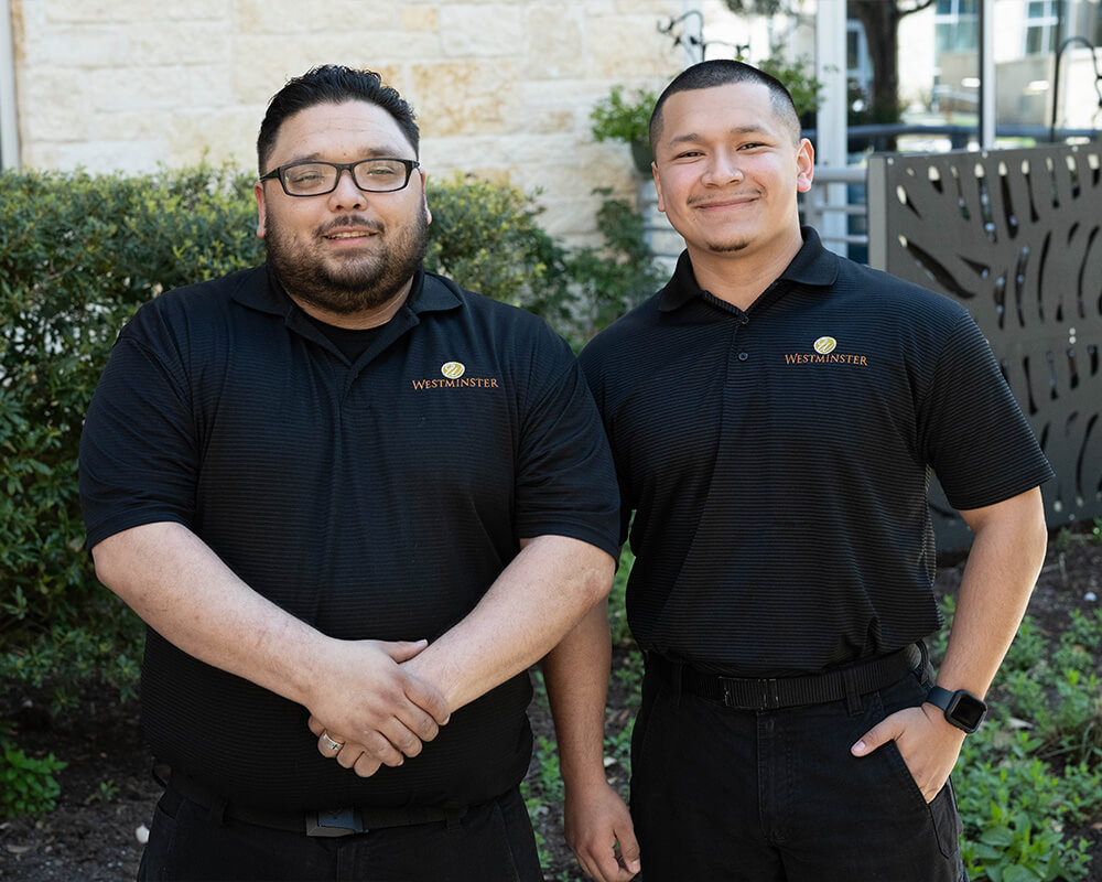 Two staff members in matching uniforms standing outside a building.