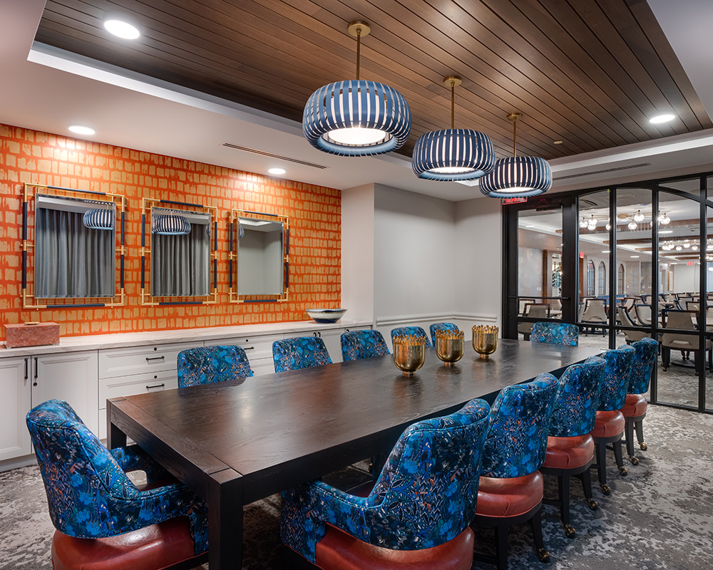 Elegant dining room with a large table and blue chairs in a senior living community.