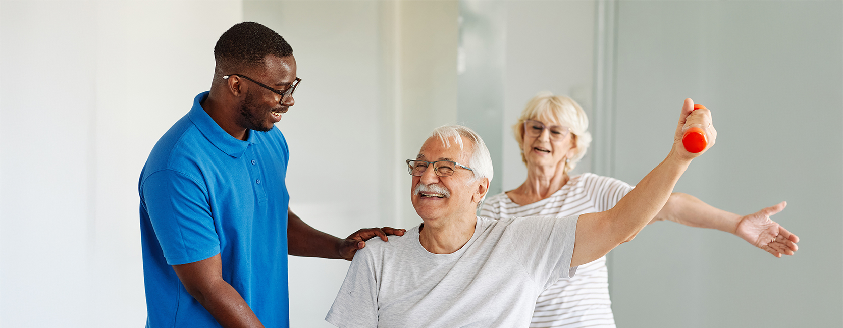 Senior man exercises with a trainer in a senior living community unit.