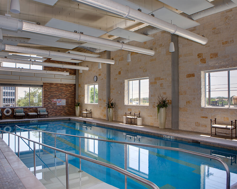 Indoor pool with natural light and seating at a senior living community.