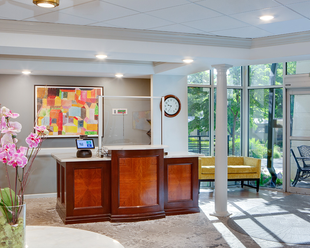 Bright lobby with wooden desk, colorful art, and large windows in a living community.