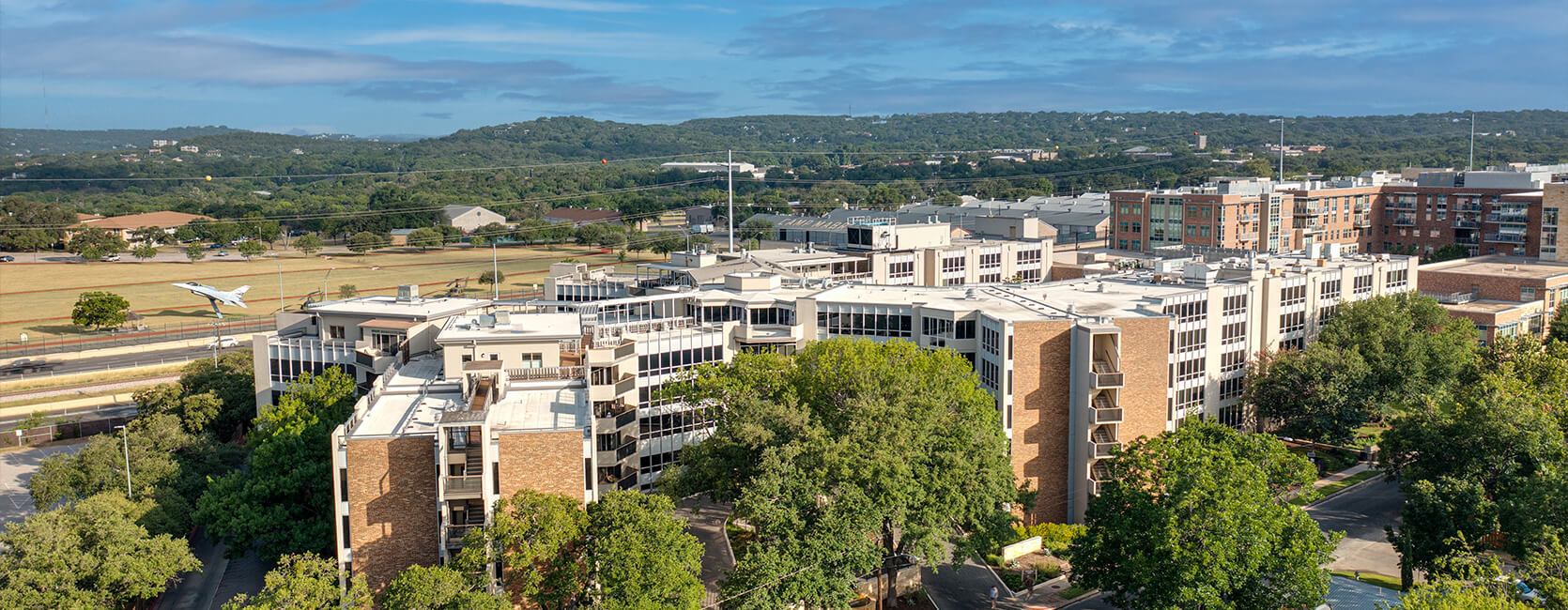 Aerial view of a modern living community with lush greenery and scenic surroundings.