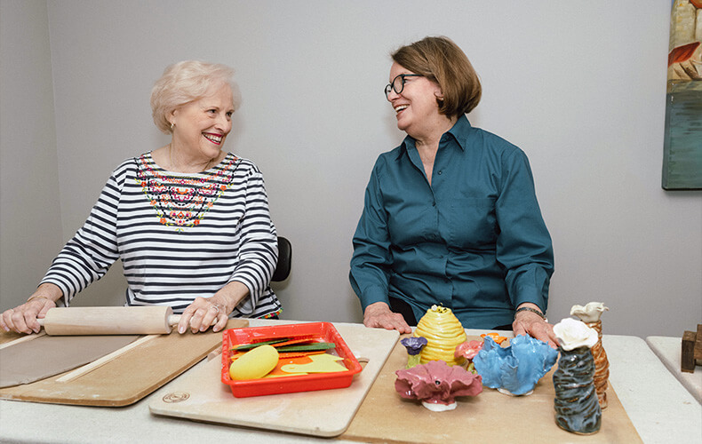 Two women in a senior living community enjoying a pottery together.