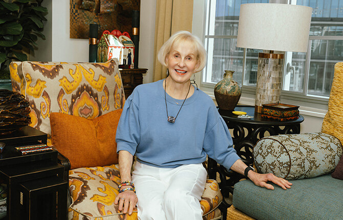 Smiling person sitting in a colorful living room within a senior living community unit.