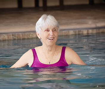 Smiling resident enjoying a swim in the indoor pool at the community center.