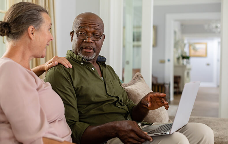 Two residents discussing something while sitting with a laptop in a units living area.