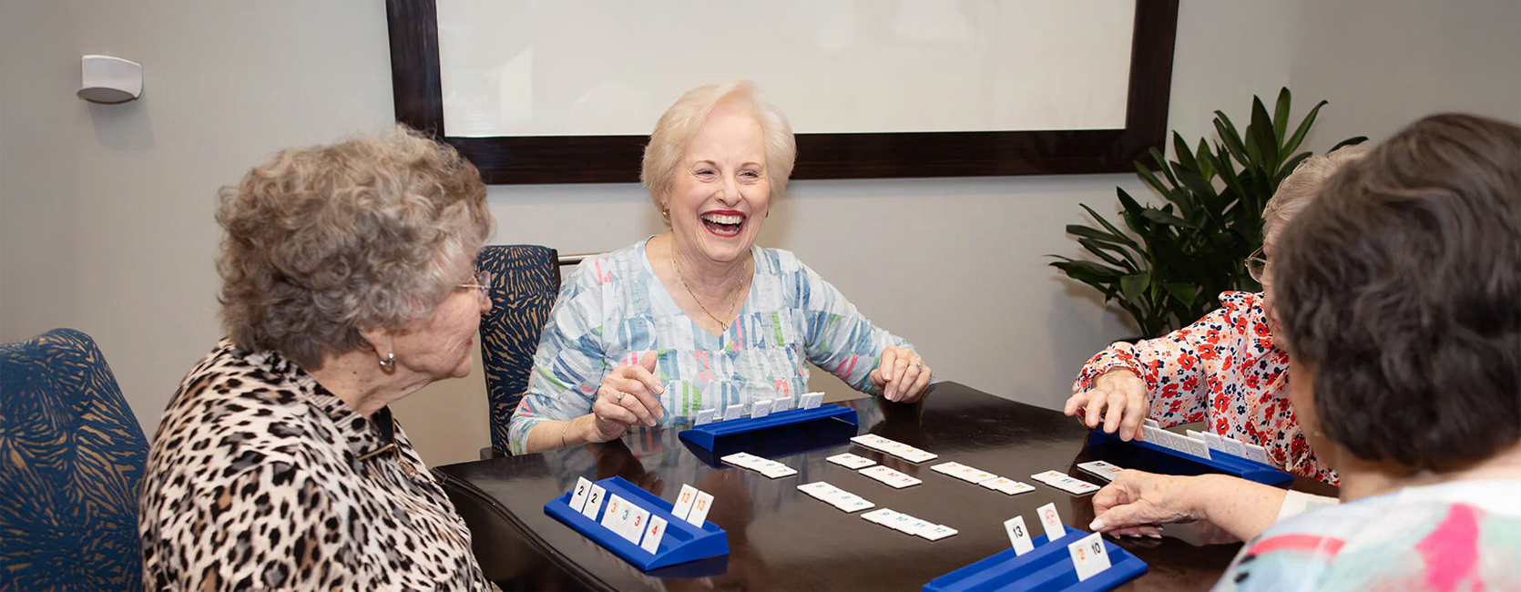 Group of seniors enjoying a game at a community table, smiling and engaging.