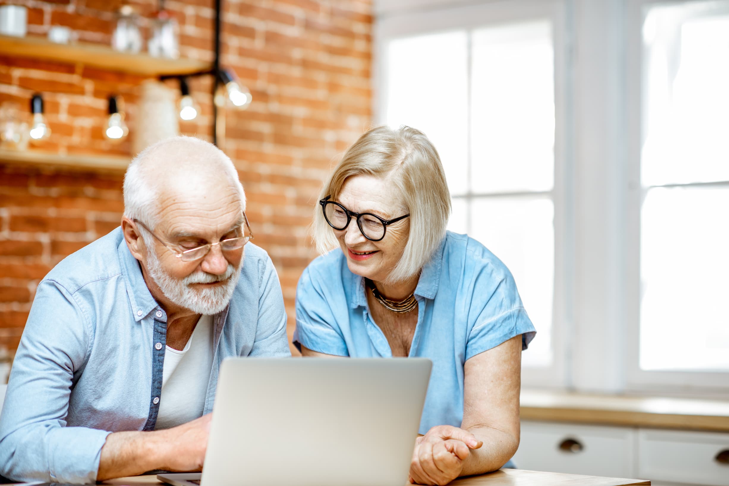 Happy couple watching webinar on their laptop in their kitchen
