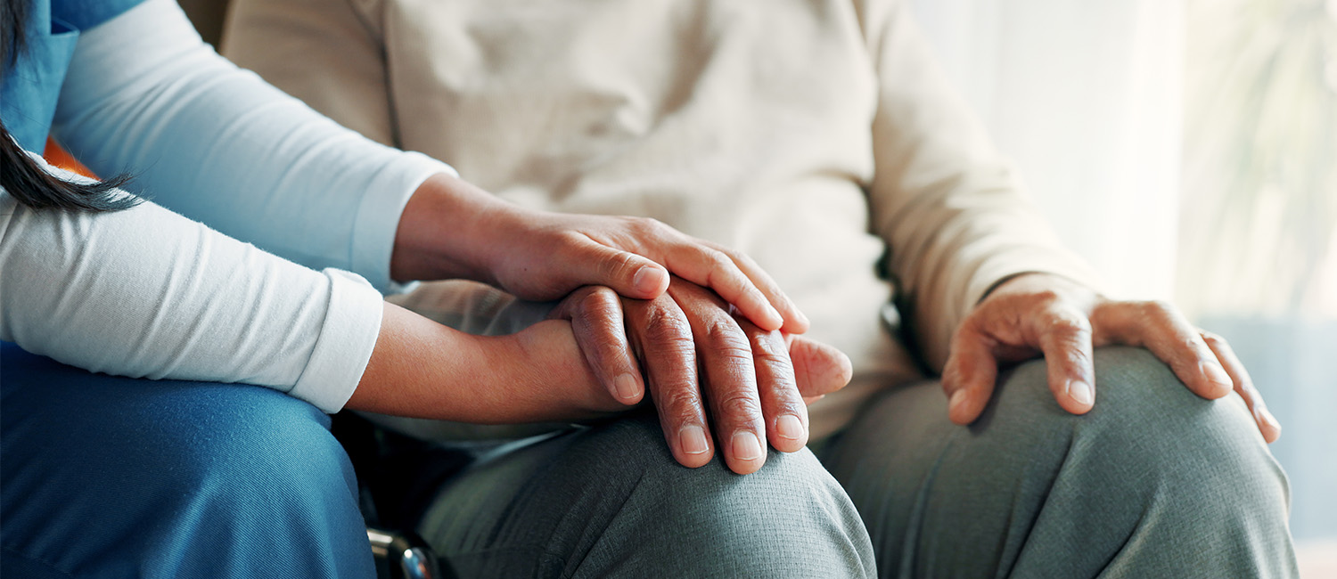 close up of caregiver holding senior man's hands