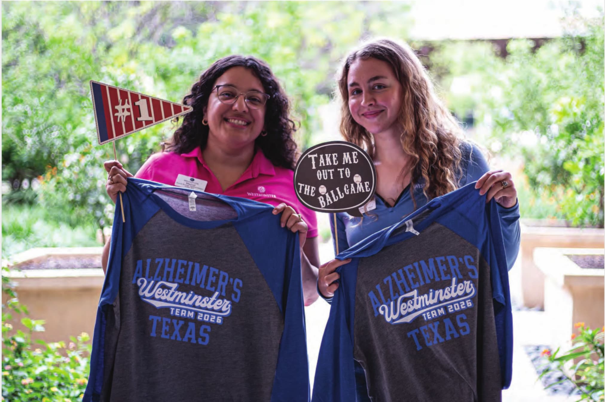 Two women holding up Westminster t-shirts and pennant flags