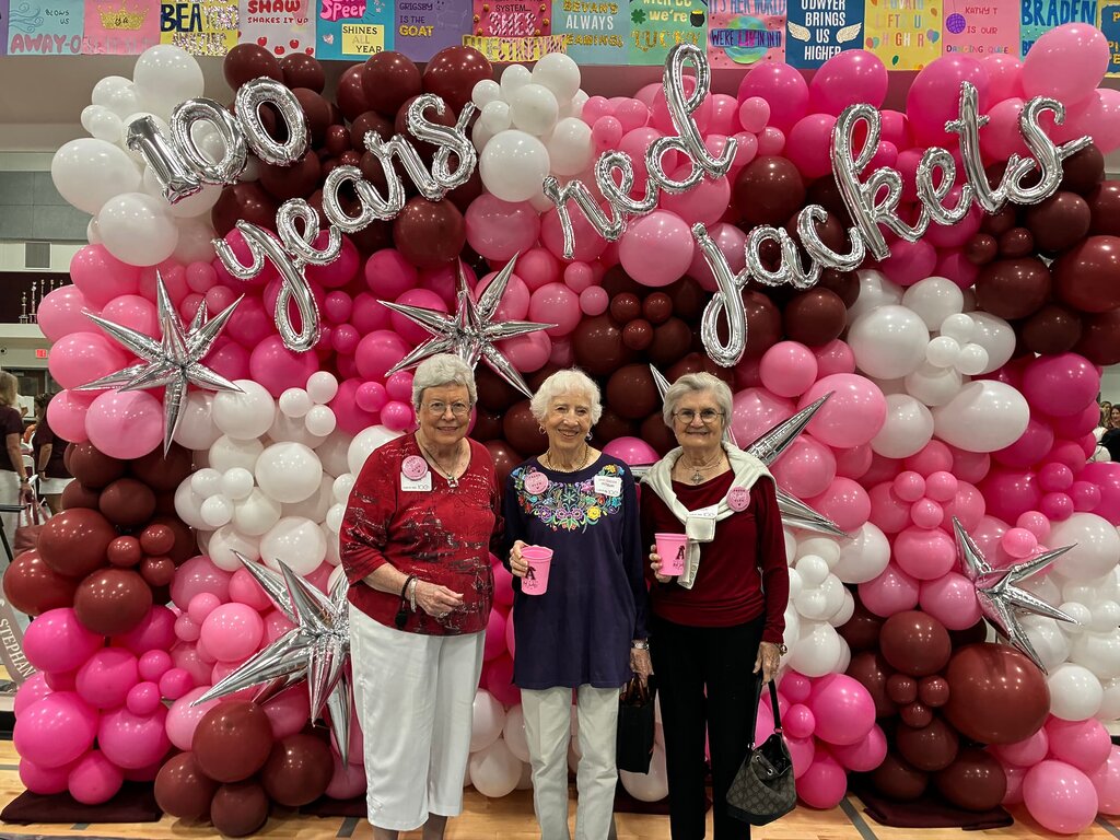 Seniors standing with wall of balloons celebrating 100 years of Red Jackets dance team
