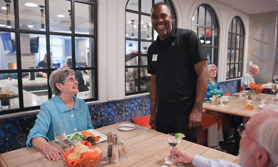 Resident and dining employee smiling during dinner service