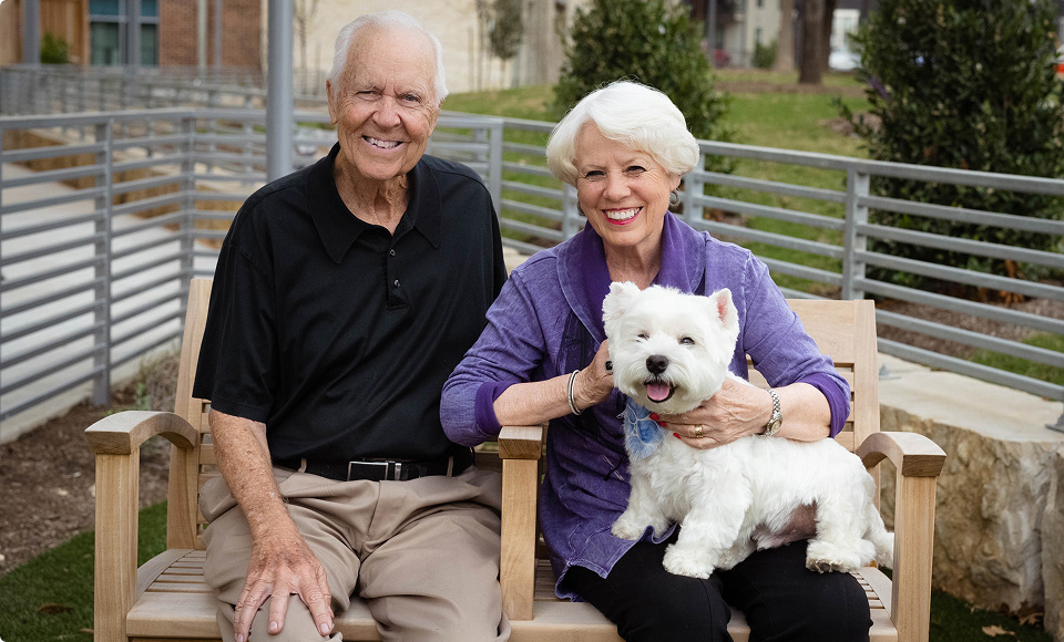 Happy senior couple and dog on a bench
