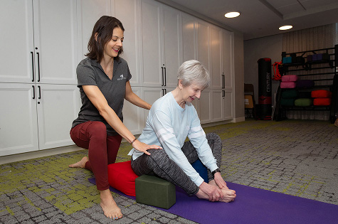 Yoga instructor helping a senior woman in a wellness room.