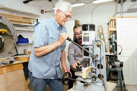 Two men using a machine in a wood workshop