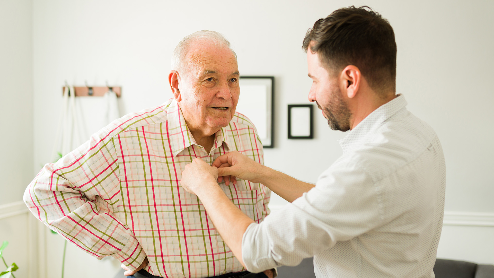 Senior man receiving assistance while getting dressed.